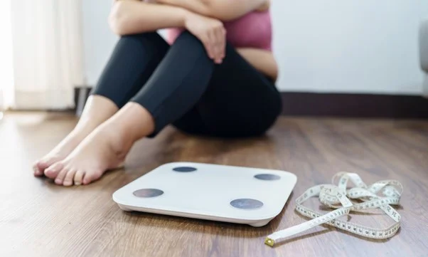 Photo of woman sitting next to a scale