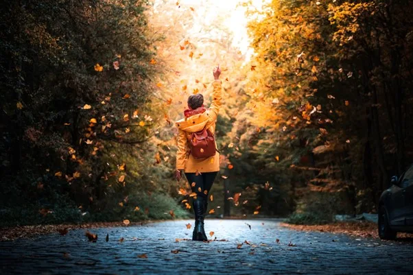 Photo of person standing in falling leaves